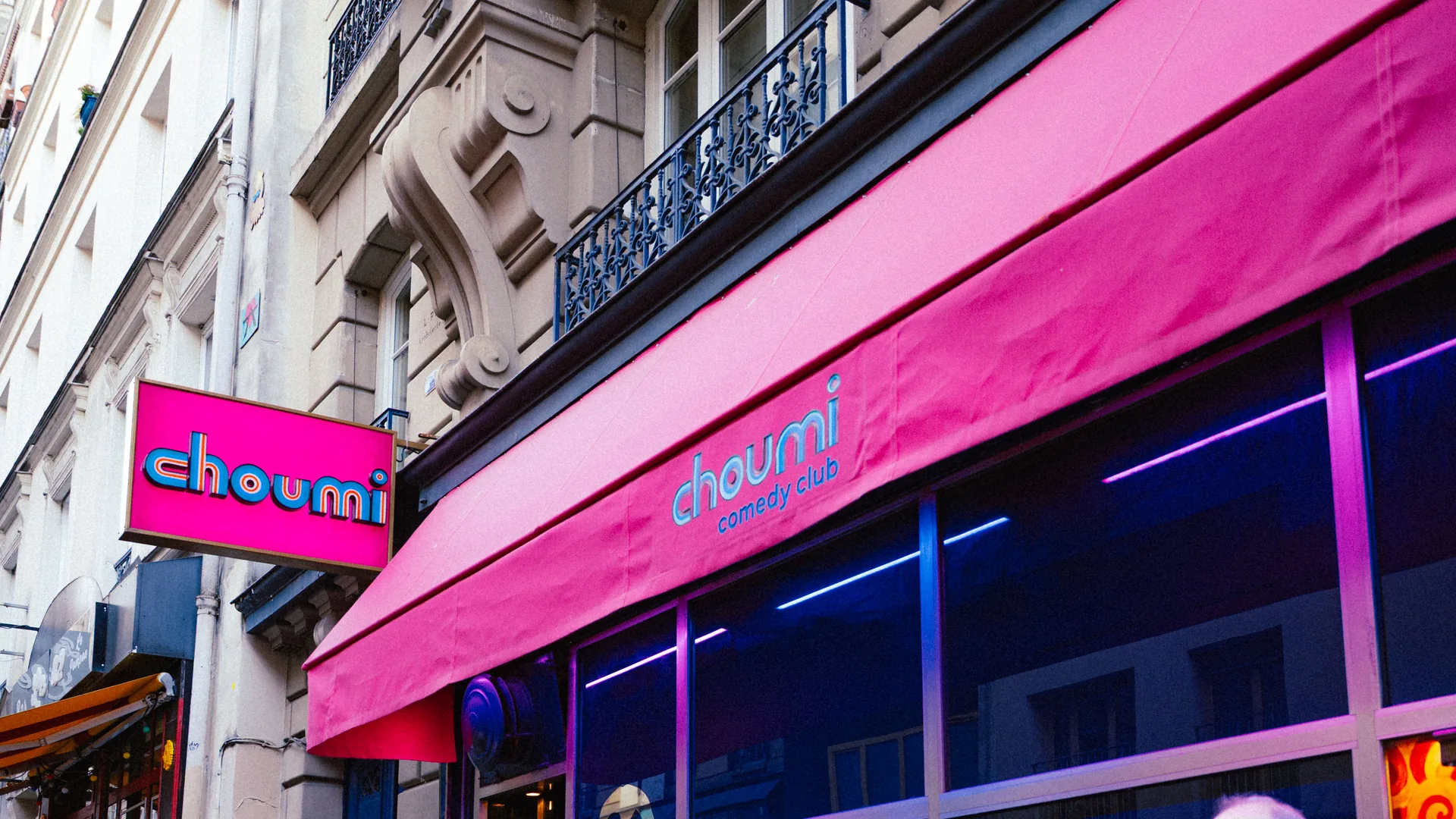 La façade du Choumi Comedy Club : enseigne et auvent rose, rue des Martyrs